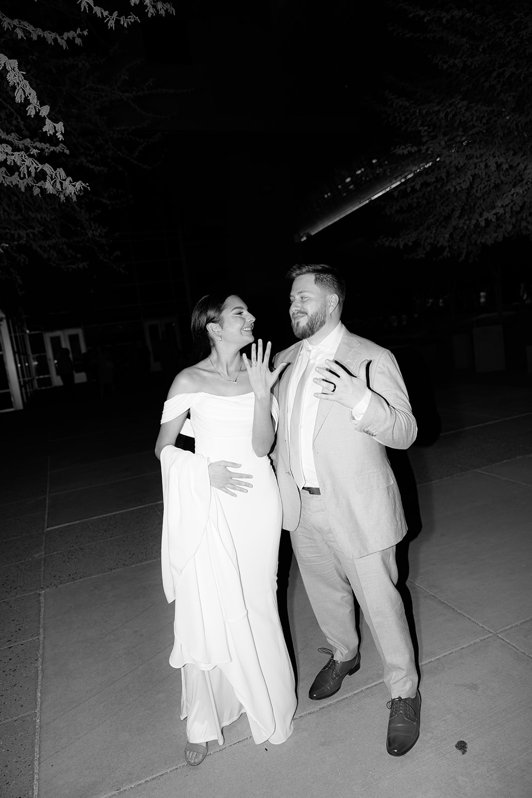 Bride and groom laughing together outside at night after their wedding, captured in black and white