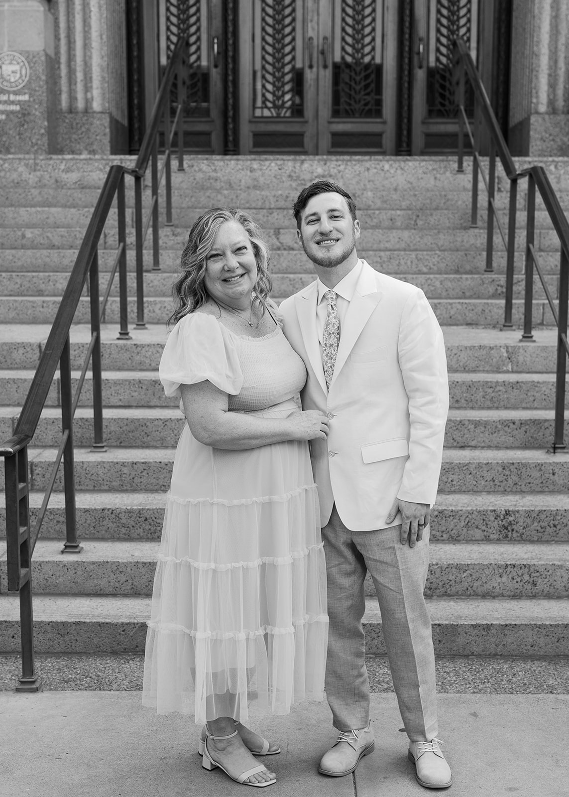 Black and white portrait of groom and family member smiling on courthouse steps during a Phoenix Courthouse Wedding