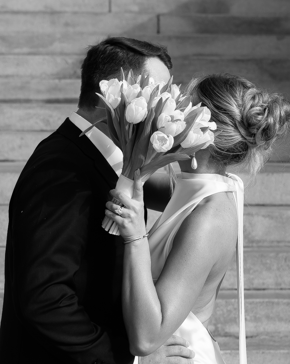 Close-up of bride holding a bouquet while leaning into groom, creating an intimate black and white portrait