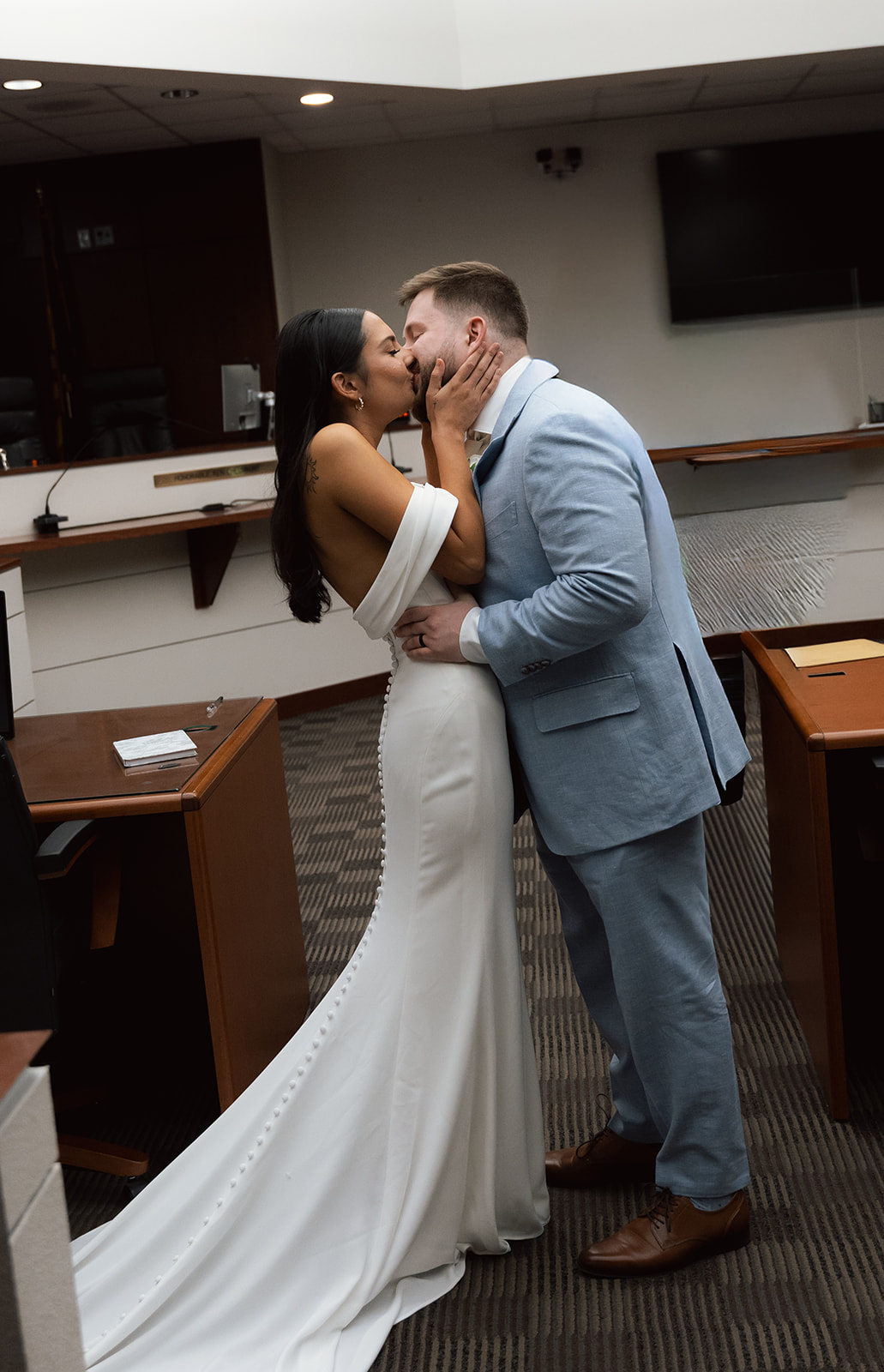 Bride and groom sharing a kiss inside a courthouse after their wedding ceremony