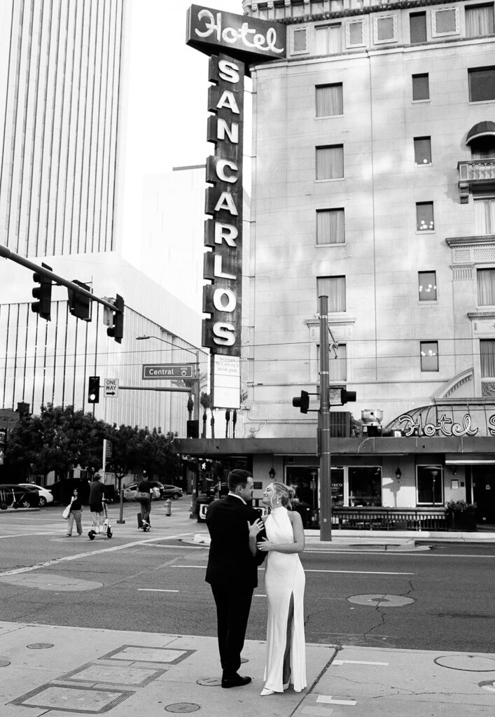 Bride and groom standing together in the street in front of Hotel San Carlos in downtown Phoenix after their courthouse wedding