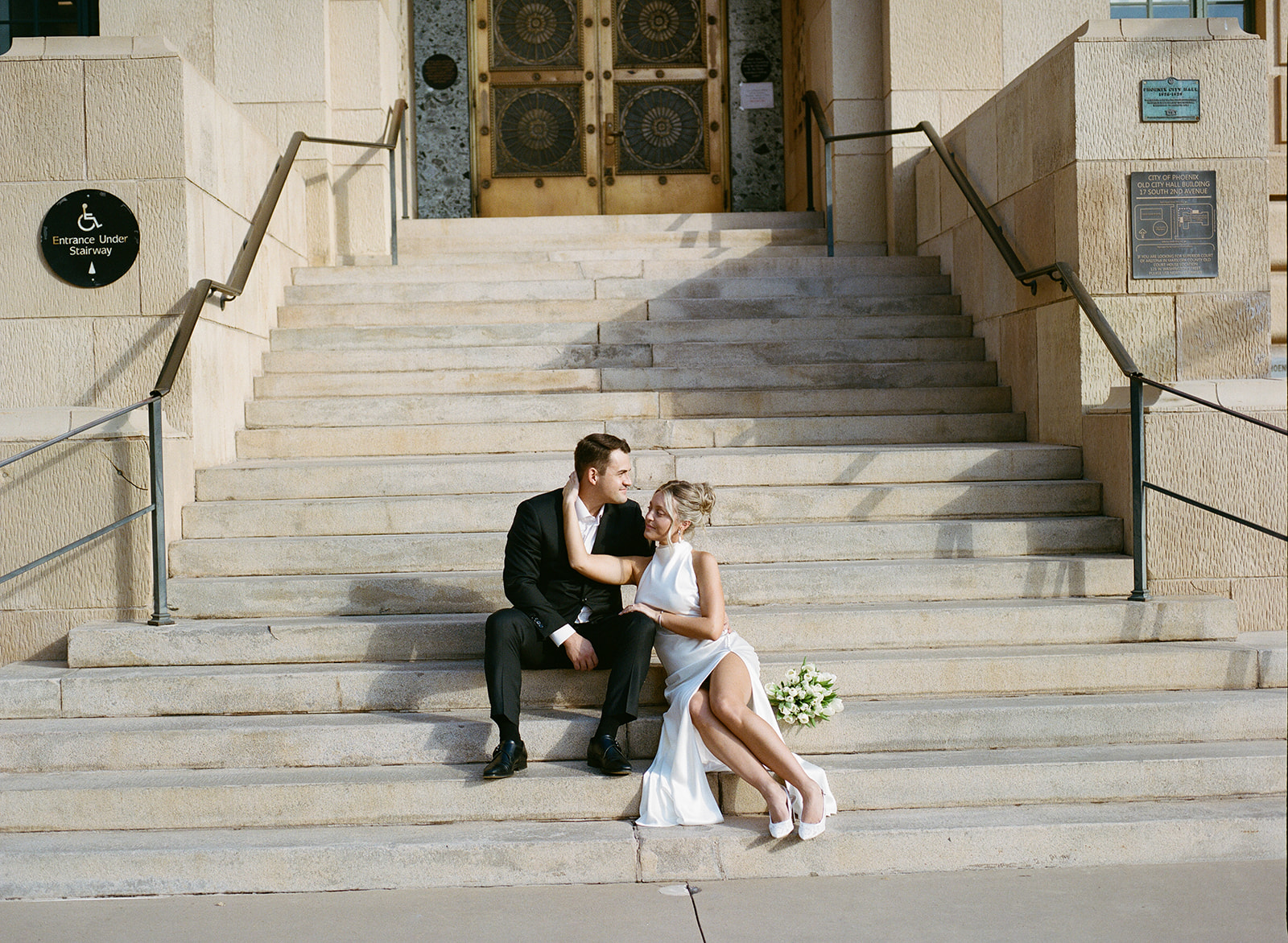 Bride and groom seated together on wide stone steps