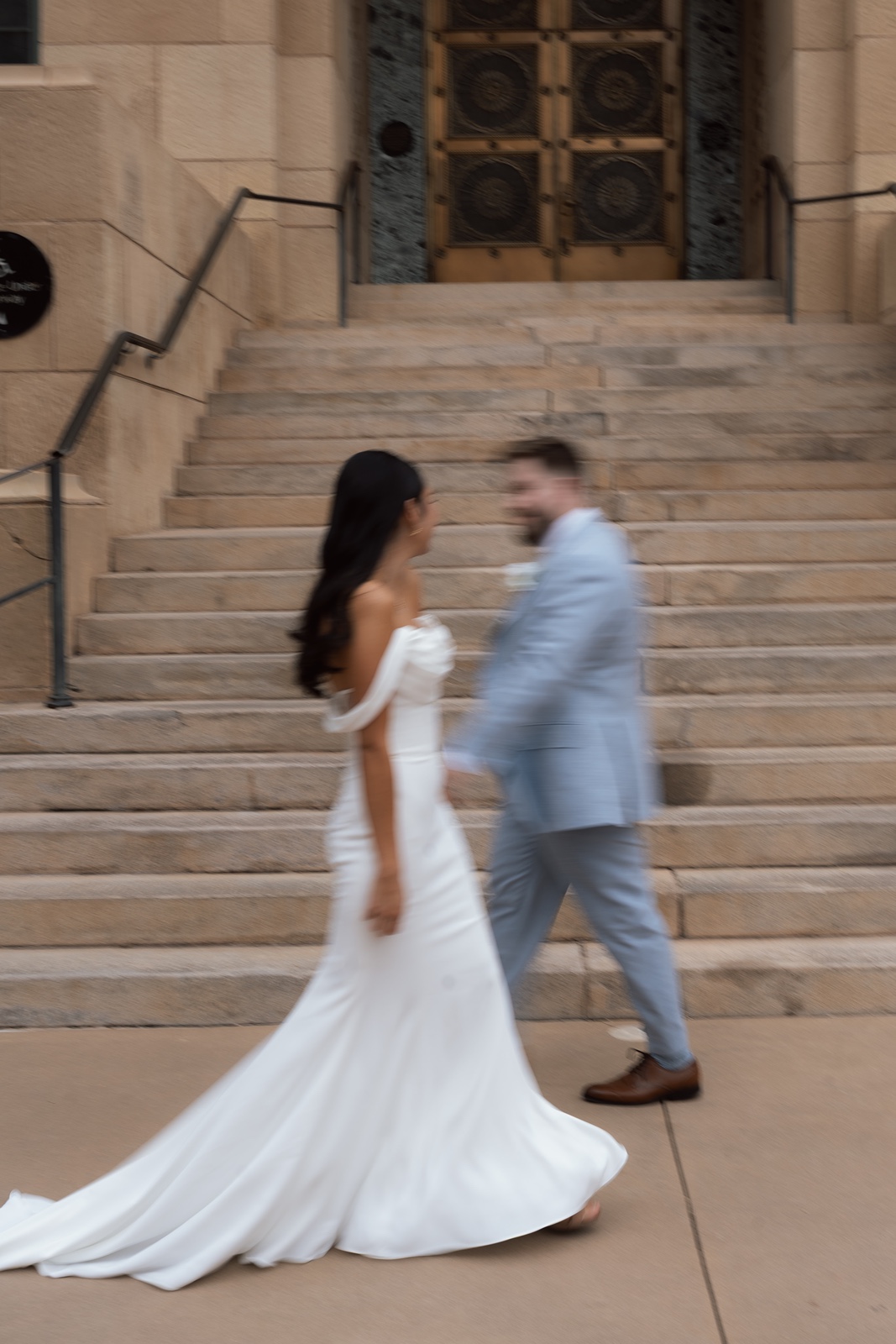 Bride and groom walking past each other on steps