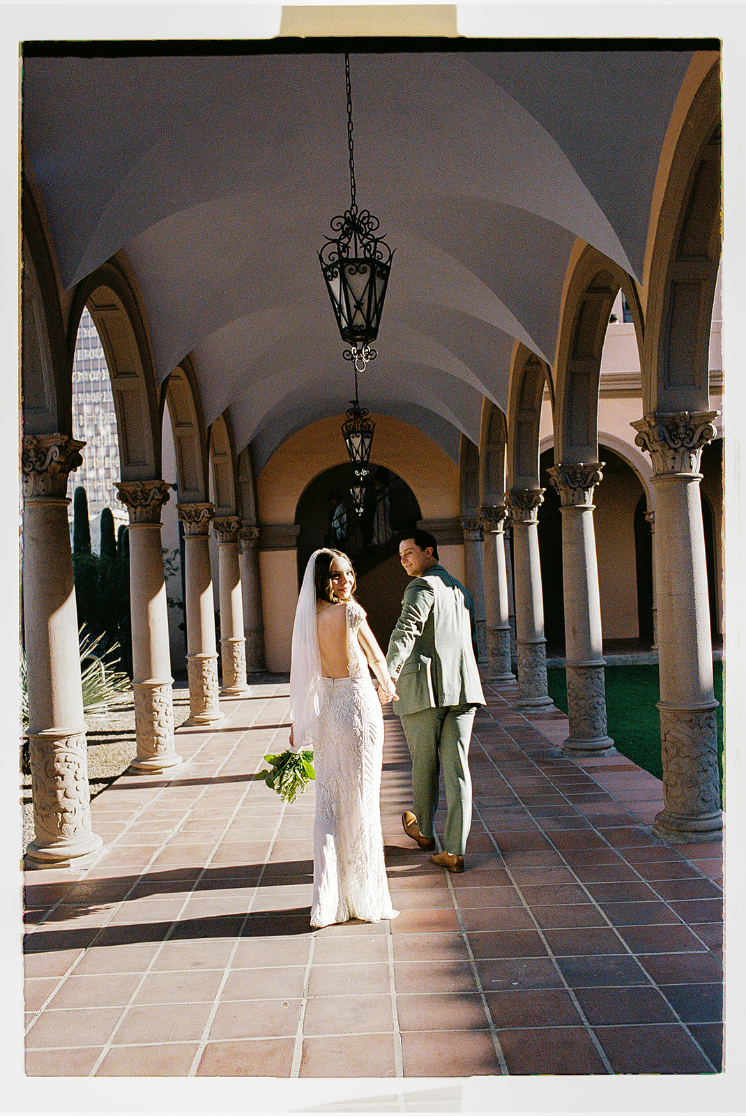 Non-traditional wedding couple posing in covered outdoor walkway