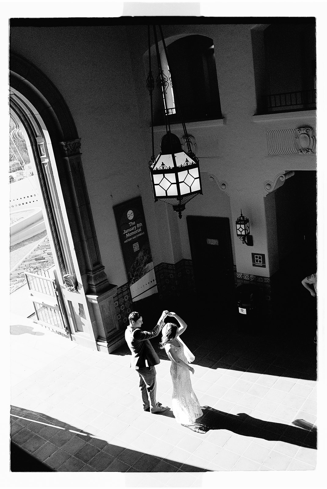 Non-traditional wedding couple walking through dramatic arched hallway