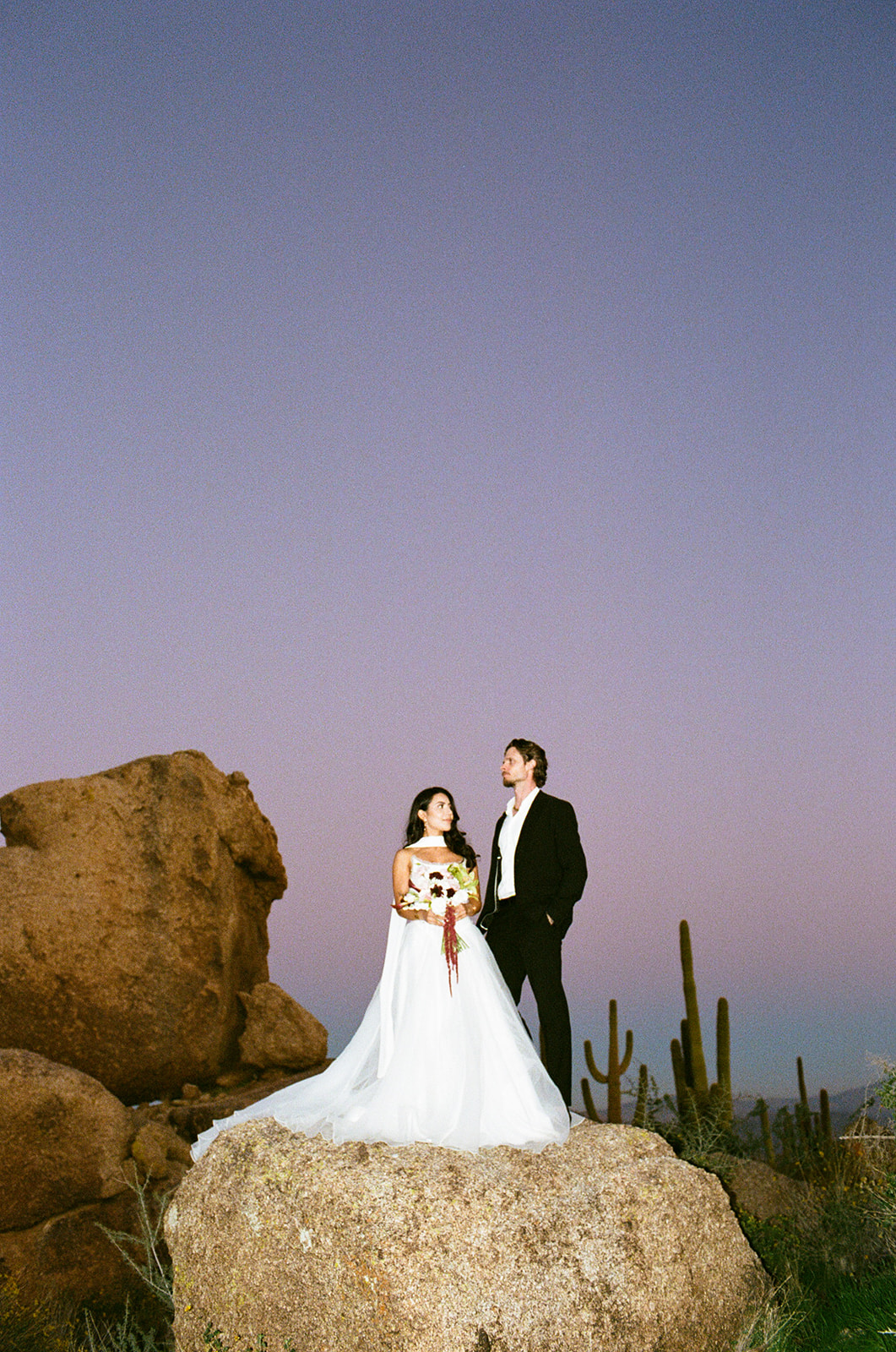 Bride and groom look at each other as the sun sets behind them