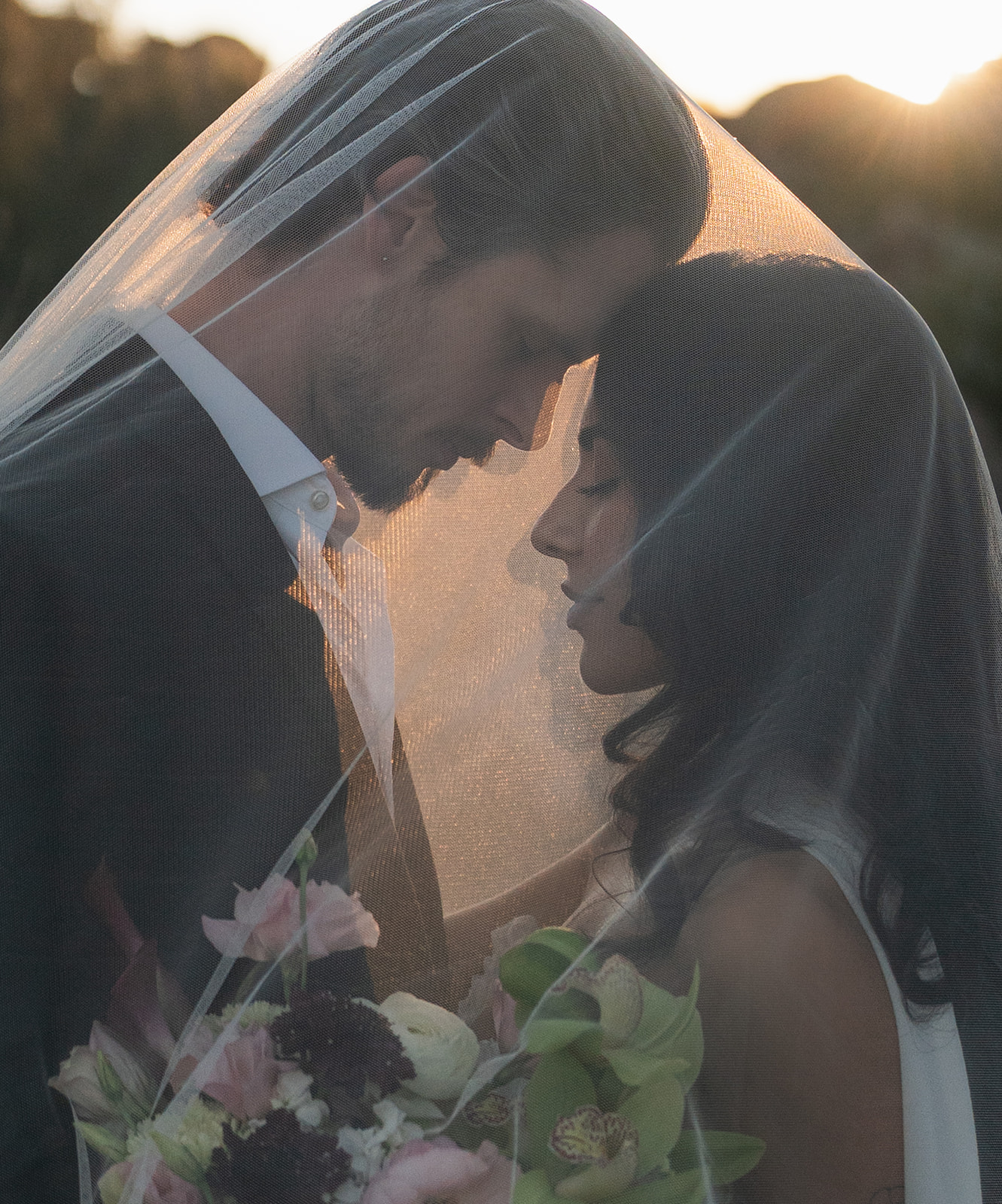 Couple sharing an intimate veil moment at sunset