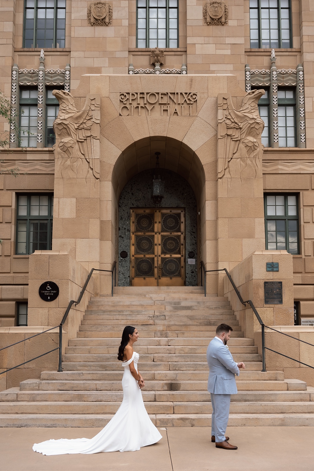 Couple standing apart in front of courthouse entrance during first look