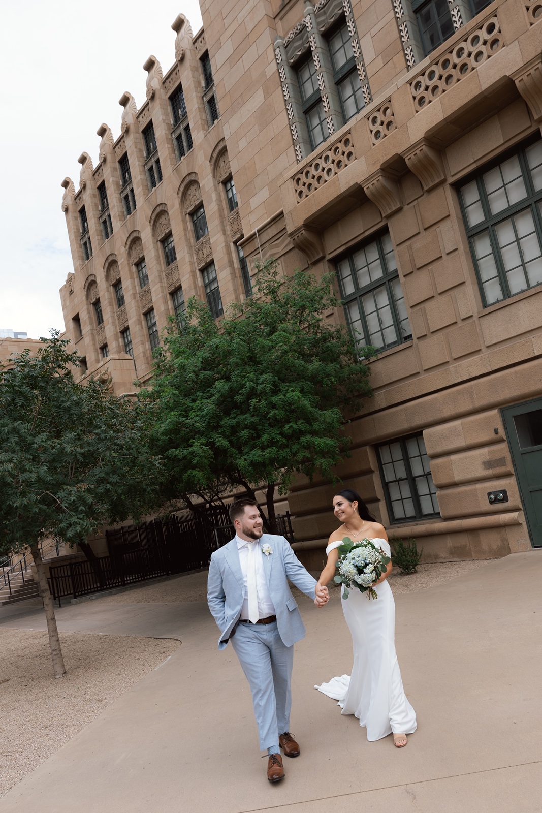Bride and groom walking outside courthouse building together
