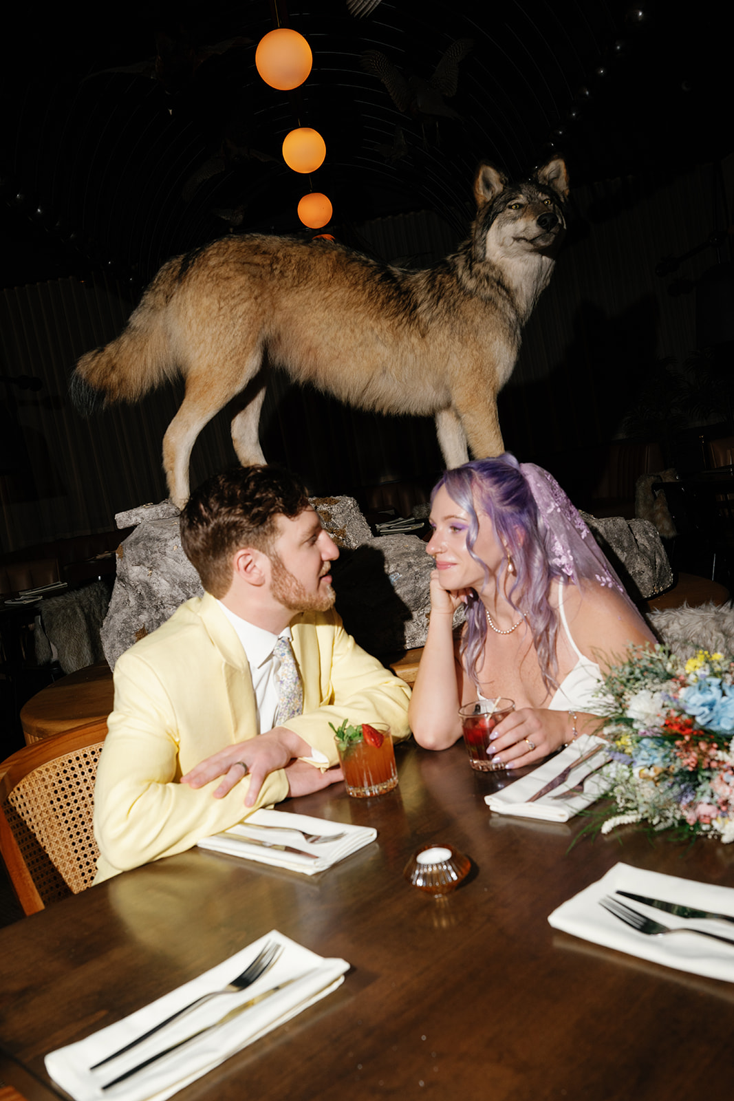 Couple seated at table with coyote statue behind them