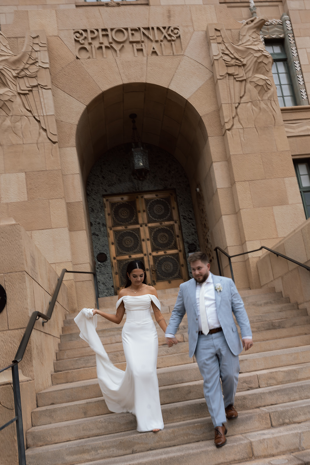 Bride and groom walking down courthouse steps together