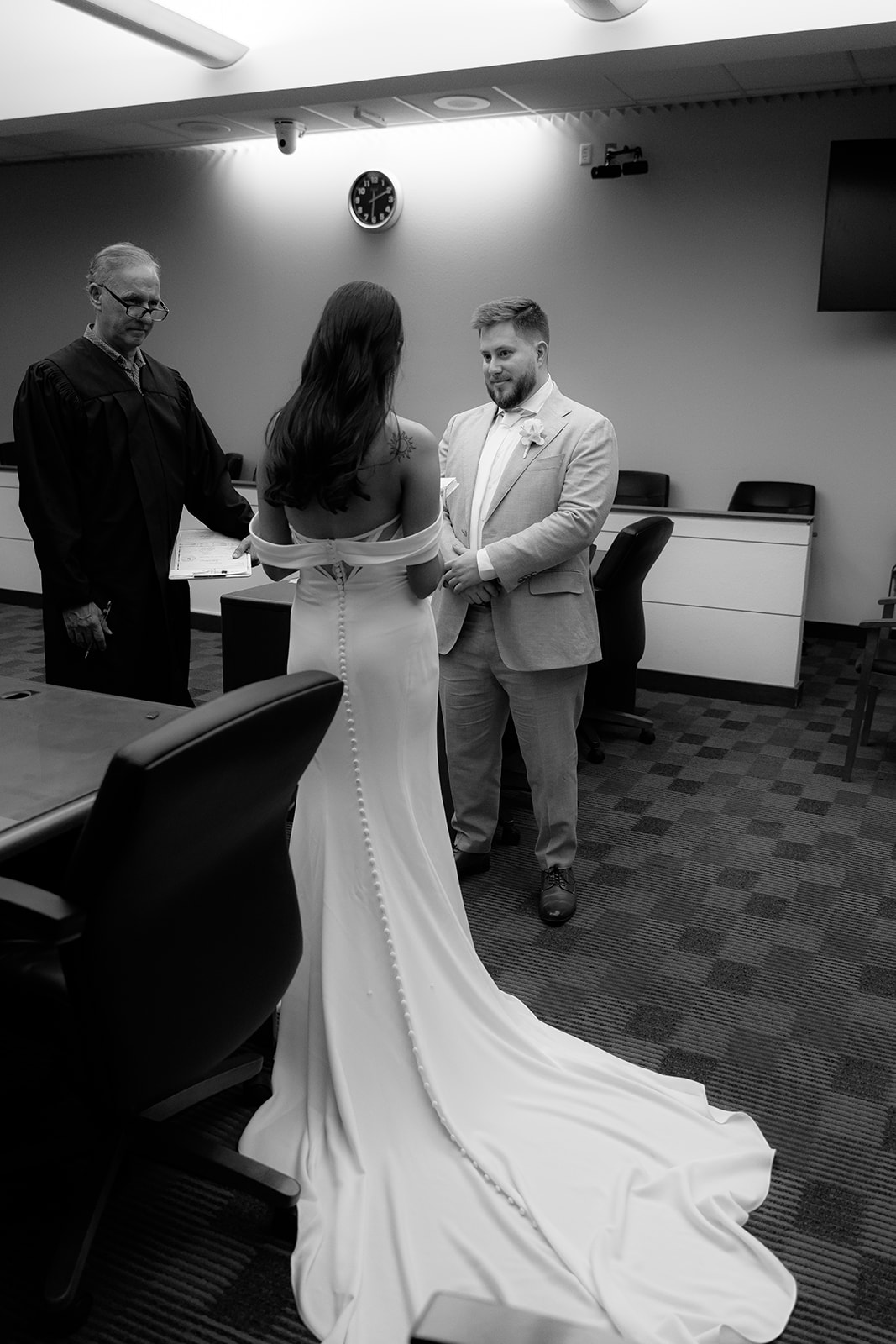 Couple standing with officiant during courthouse wedding ceremony