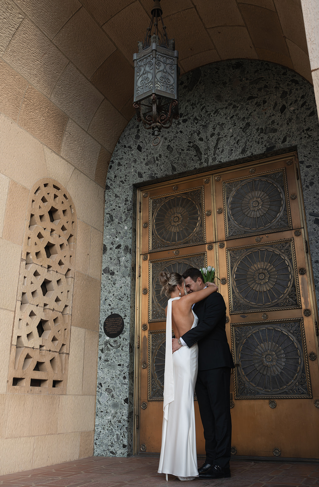 Couple embracing in front of ornate doors during a Phoenix Courthouse Wedding in downtown Phoenix