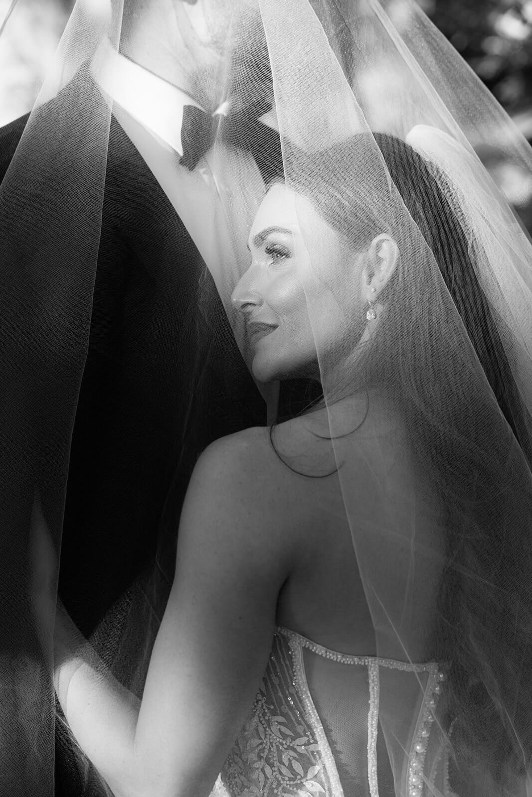 Black and white portrait of a bride under her veil with groom at a San Luis Obispo wedding venue, capturing an intimate, romantic moment.