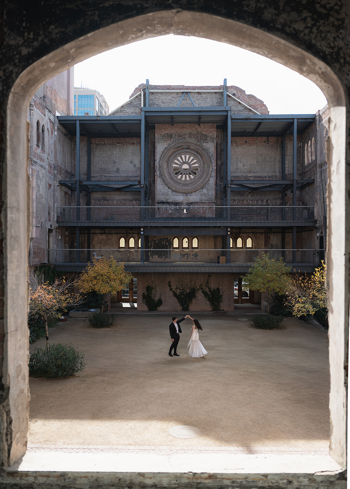 Wide shot of couple holding hands beneath a grand historic building in downtown wedding venues in Phoenix Arizona— The Abbey at Monroe