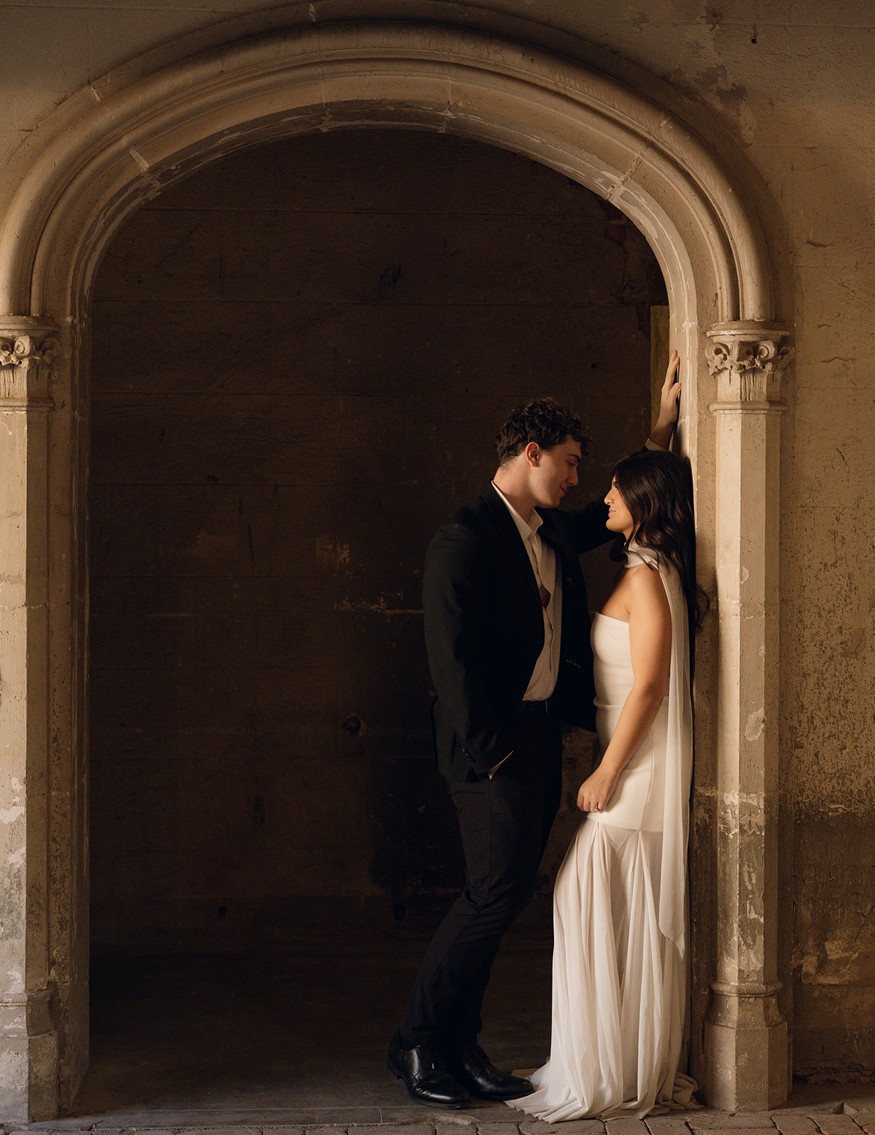 Couple standing under an arched stone entryway at romantic wedding venue in Phoenix Arizona—The Abbey at Monroe