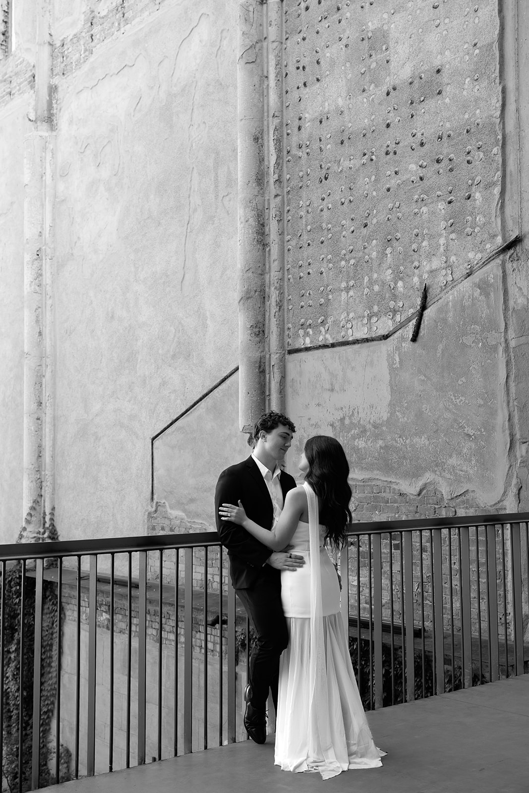 Bride and groom embracing and smiling at each other in soft daylight with a textured wall behind them at wedding venues in Phoenix Arizona— The Abbey at Monroe