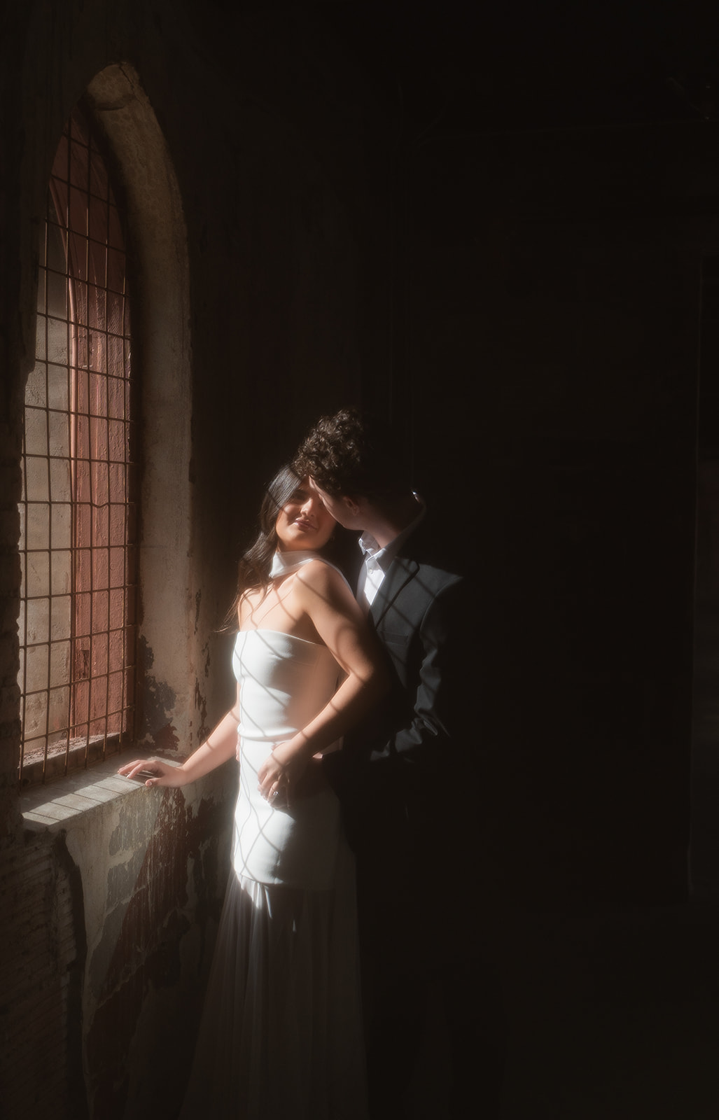 Romantic close-up shot of couple leaning together in front of an arched window with soft shadows cast on them both at elegant wedding venues in Phoenix Arizona— The Abbey on Monroe