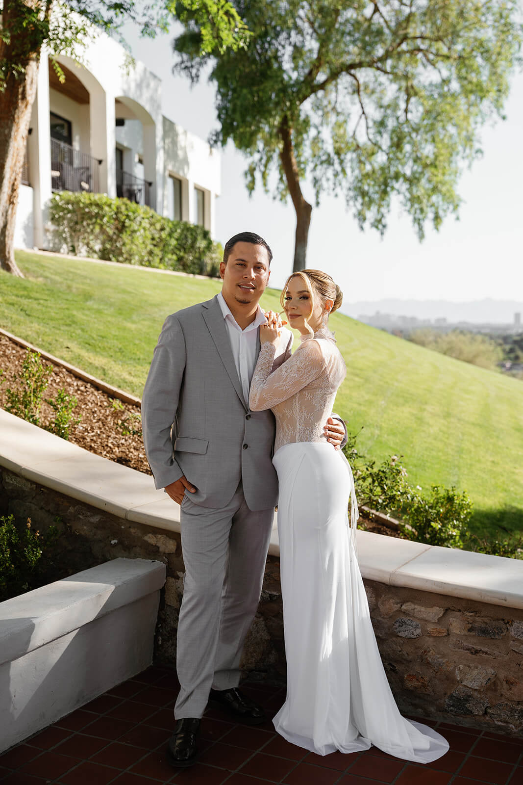 Bride and groom posing together outdoors at a scenic micro wedding venue, with lush greenery and hillside views in the background.