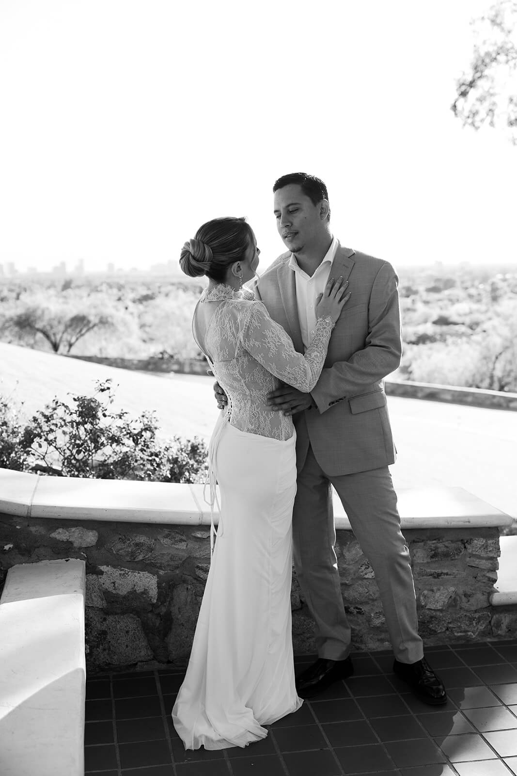 Black and white photo of bride and groom embracing on a terrace overlooking the city at an intimate micro wedding venue.