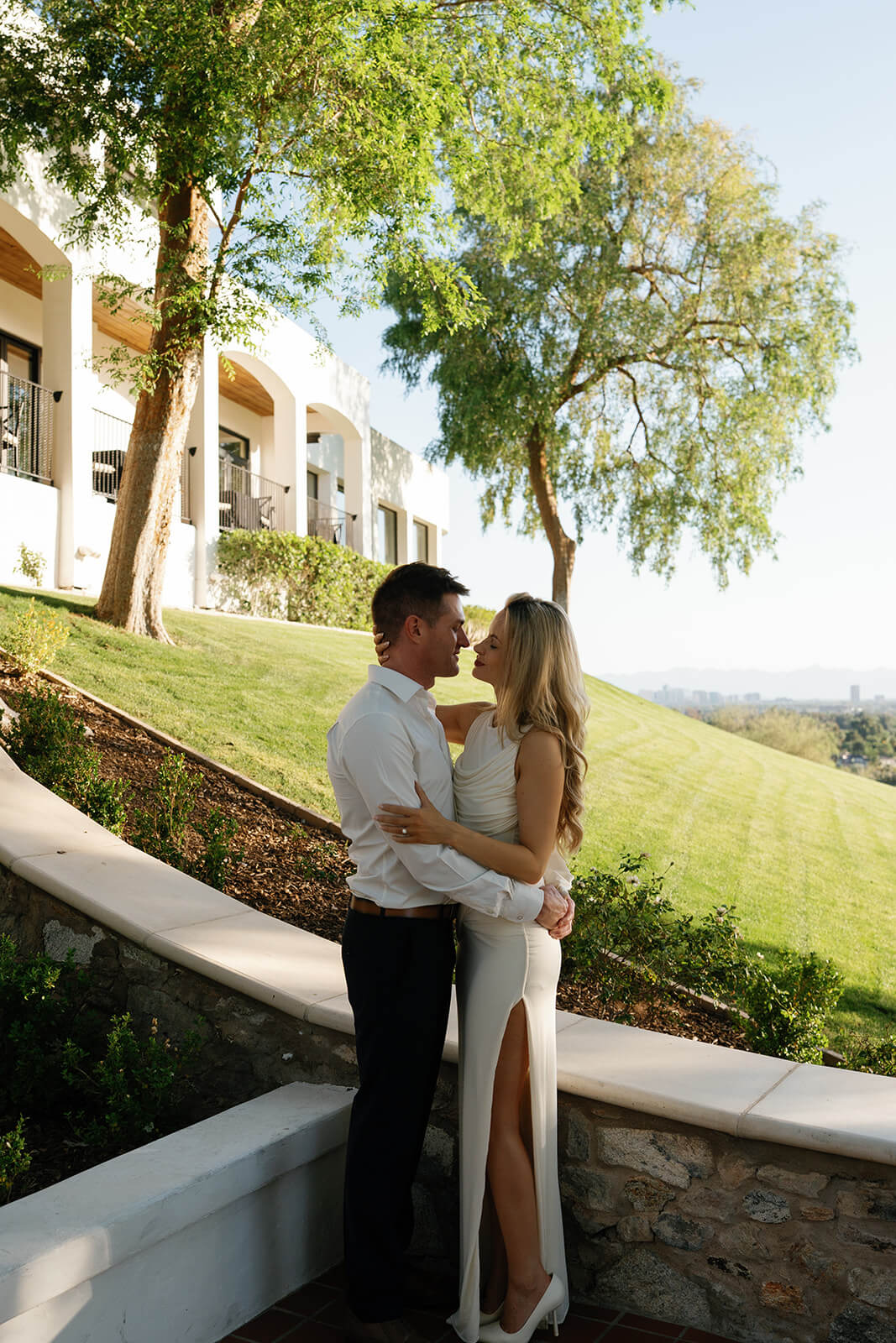 Couple embracing on terrace overlooking hillside at Wrigley Mansion wedding venue in Arizona with scenic outdoor views