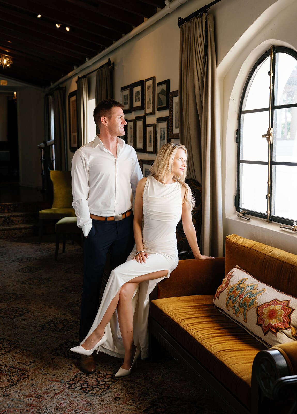Couple looking out window together at Wrigley Mansion wedding venue in Phoenix Arizona with soft light and cozy lounge seating