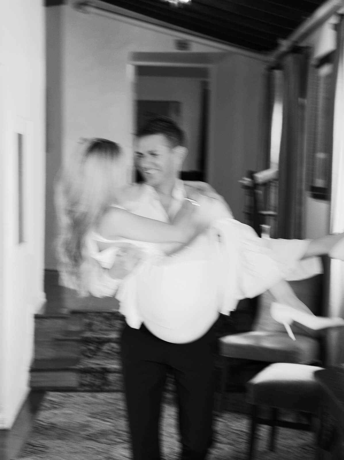 Motion blur black and white photo of groom carrying bride at Wrigley Mansion wedding venue in Phoenix Arizona capturing movement and energy
