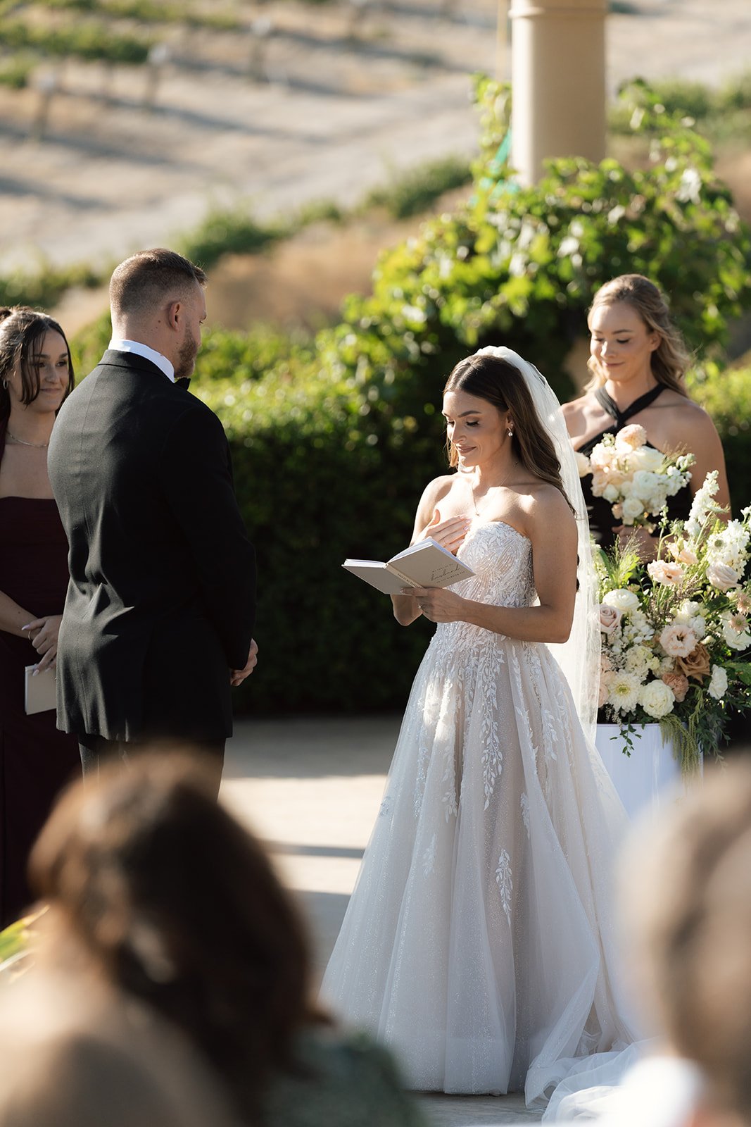 Bride reading her vows during a small outdoor ceremony at an intimate wedding venue in California with floral arrangements and vineyard views at Villa San Juliette