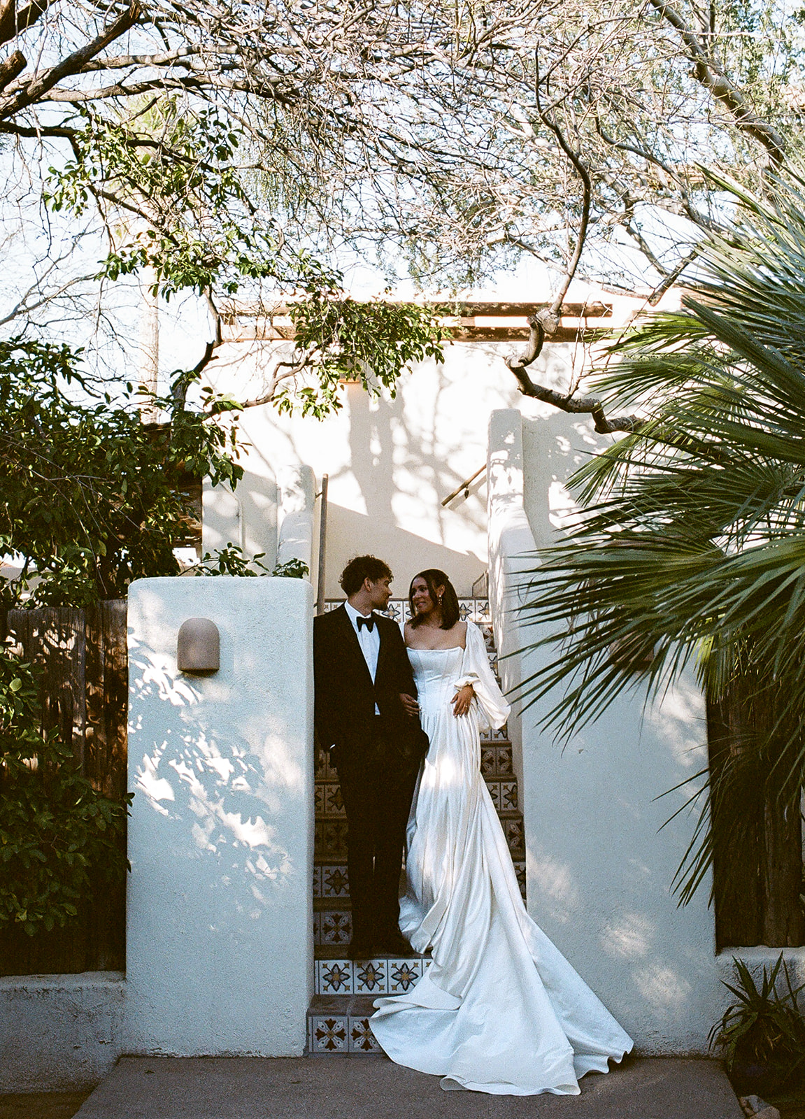 Couple framed by greenery and white courtyard walls