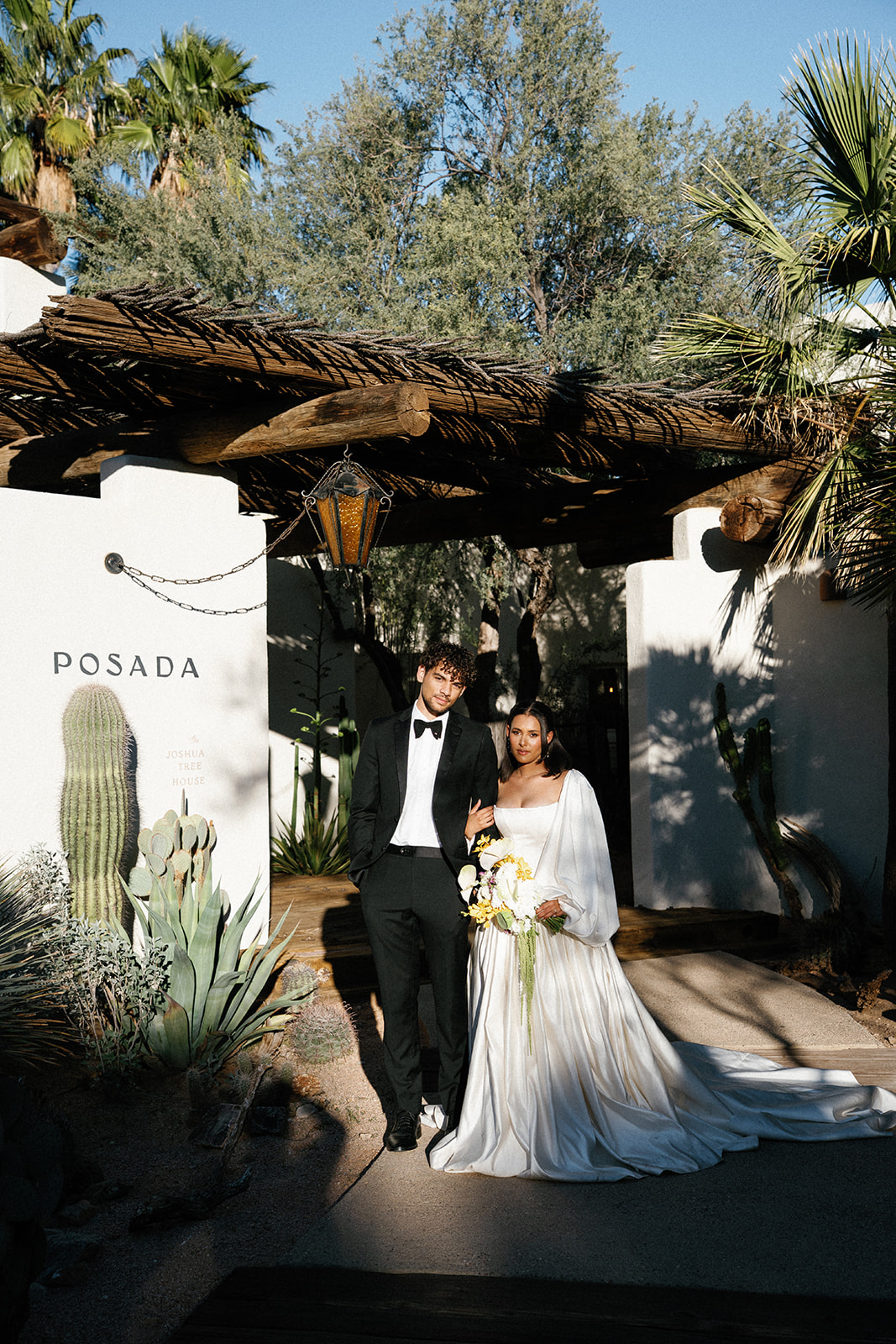 Couple walks under rustic wooden entry in desert setting