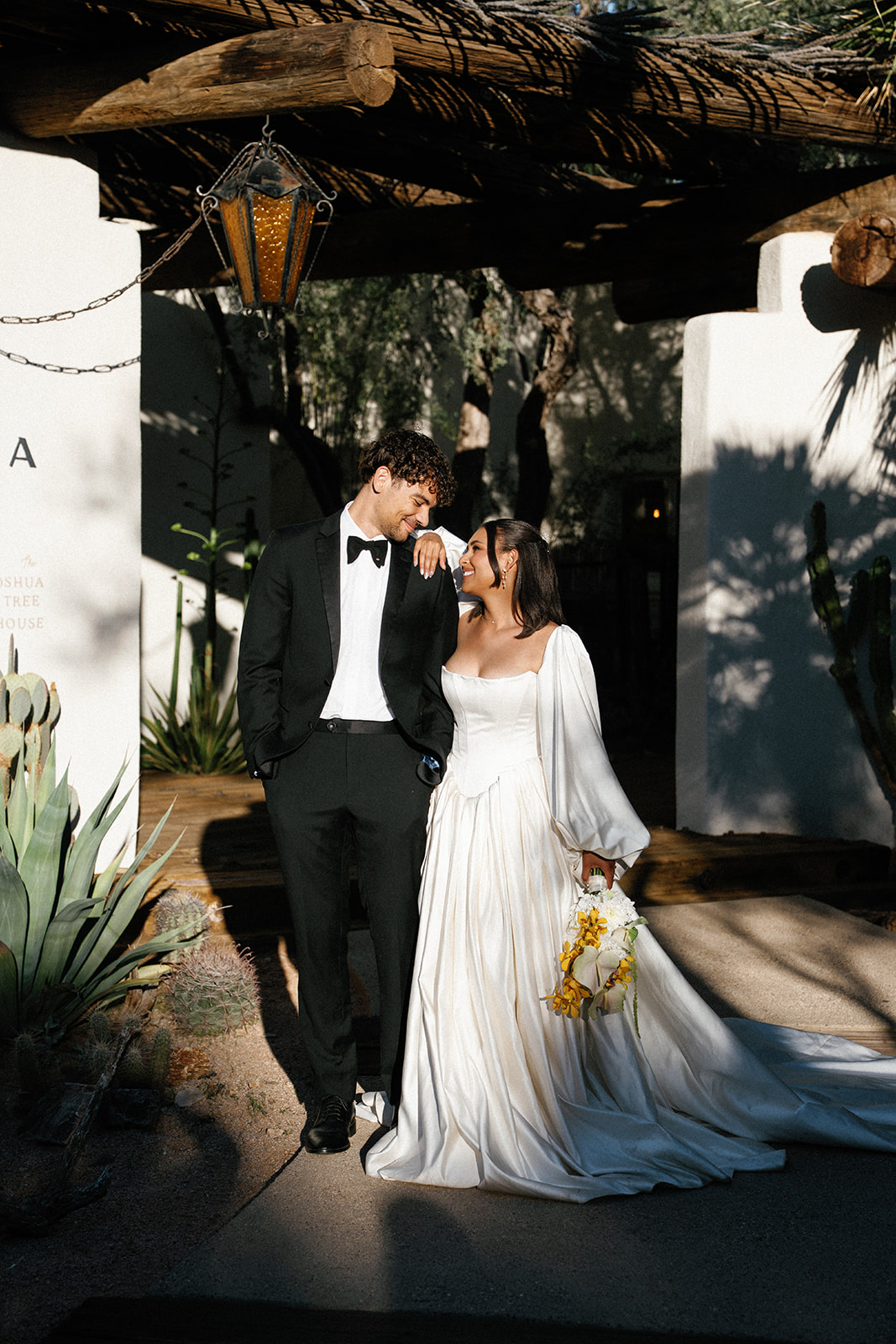 Newlyweds stroll beneath shade at Joshua Tree House Tucson wedding
