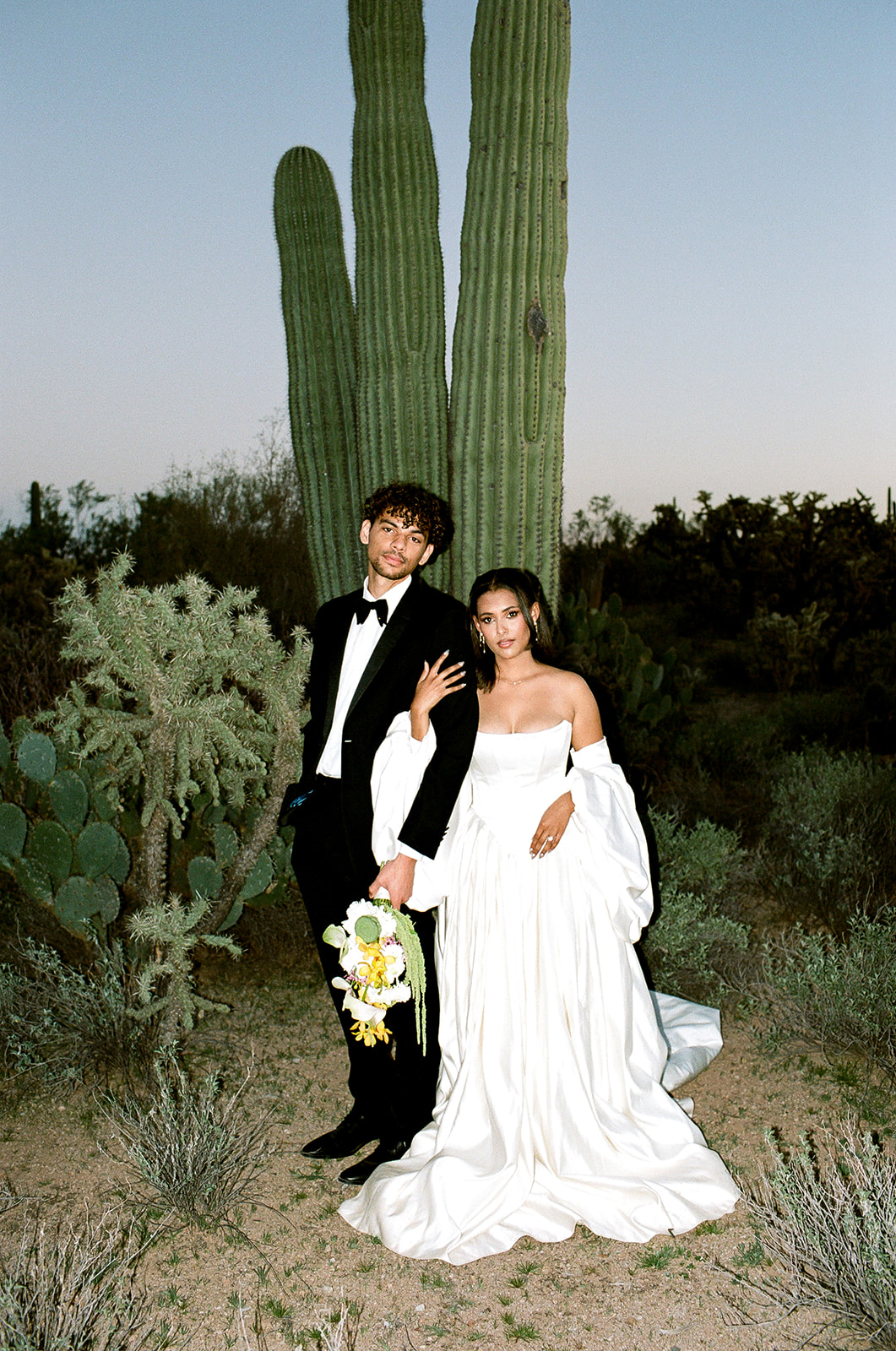 Bride and groom pose by cactus at Joshua Tree House Tucson wedding
