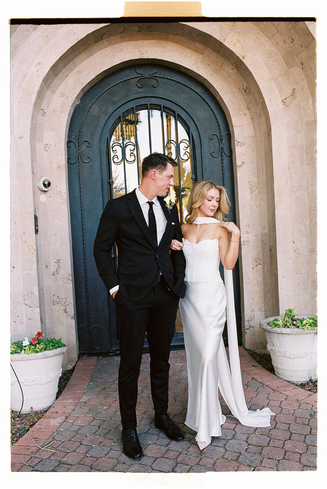 Stylish bride and groom posing in front of arched stone architecture during an intimate elopement celebration