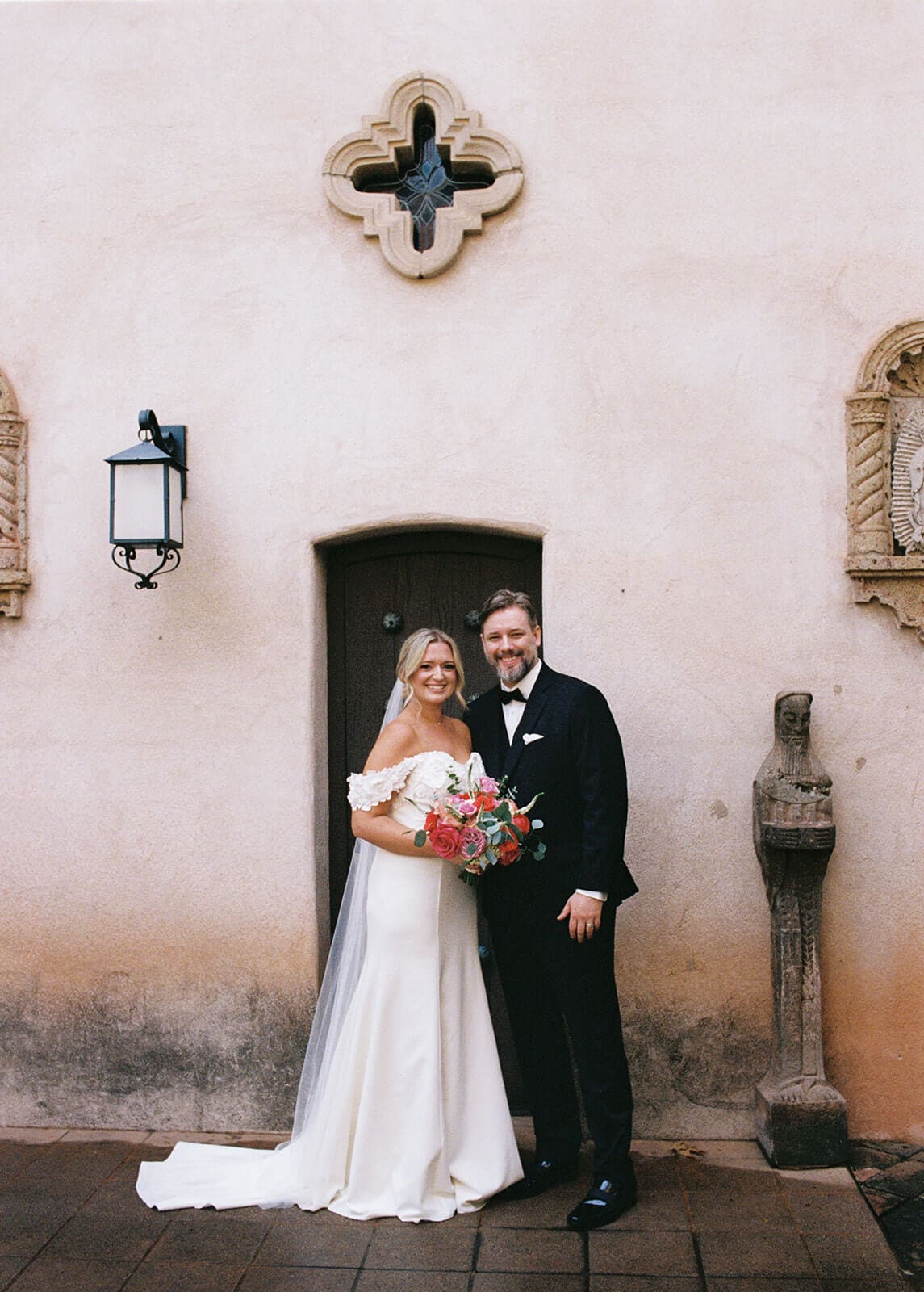 Bride and groom standing together in front of a stucco wall during a micro wedding at Tlaquepaque.