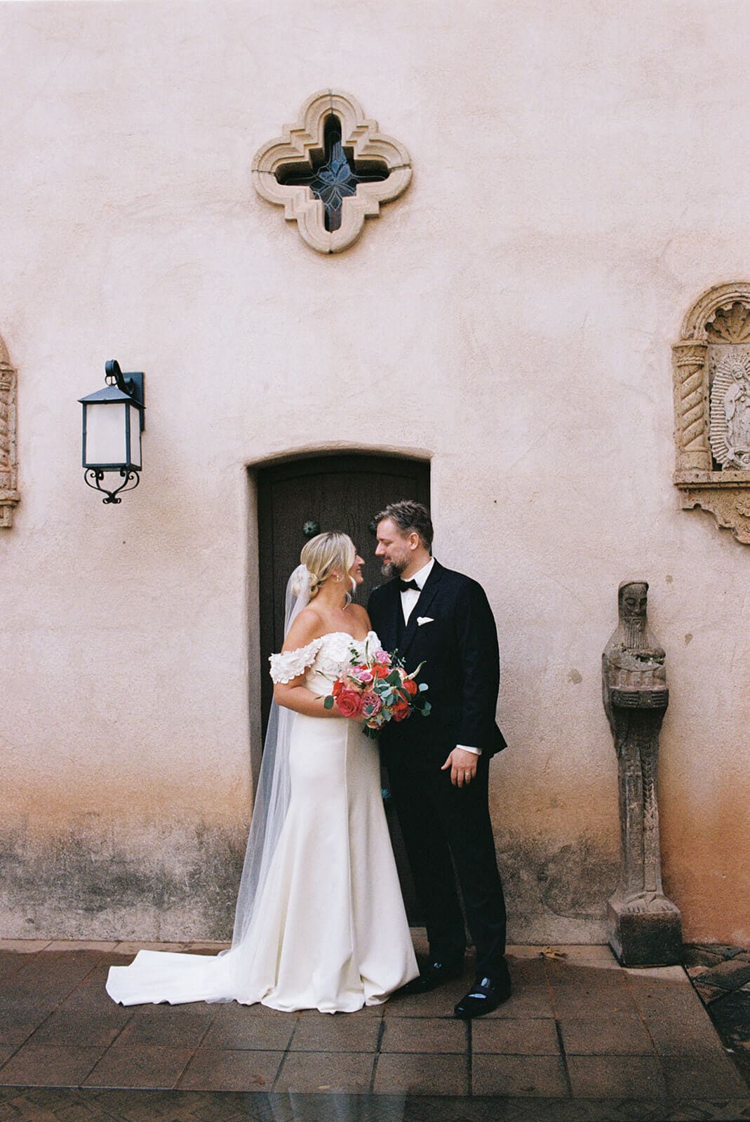 Bride and groom embracing in front of a stucco wall during a micro wedding at Tlaquepaque.