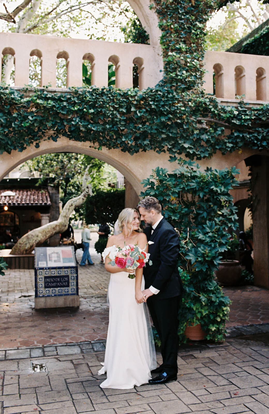 Bride and groom standing together beneath ivy-covered arches during a micro wedding at Tlaquepaque.