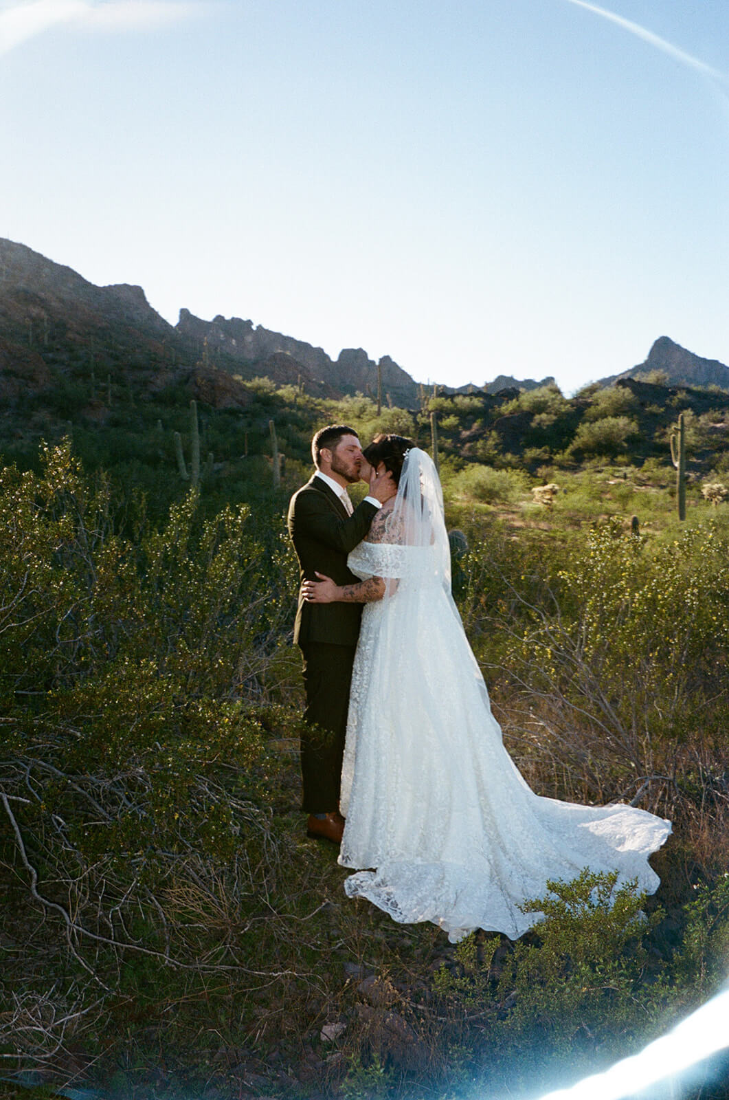 Couple kissing in the desert surrounded by mountain views during an intimate wedding ceremony