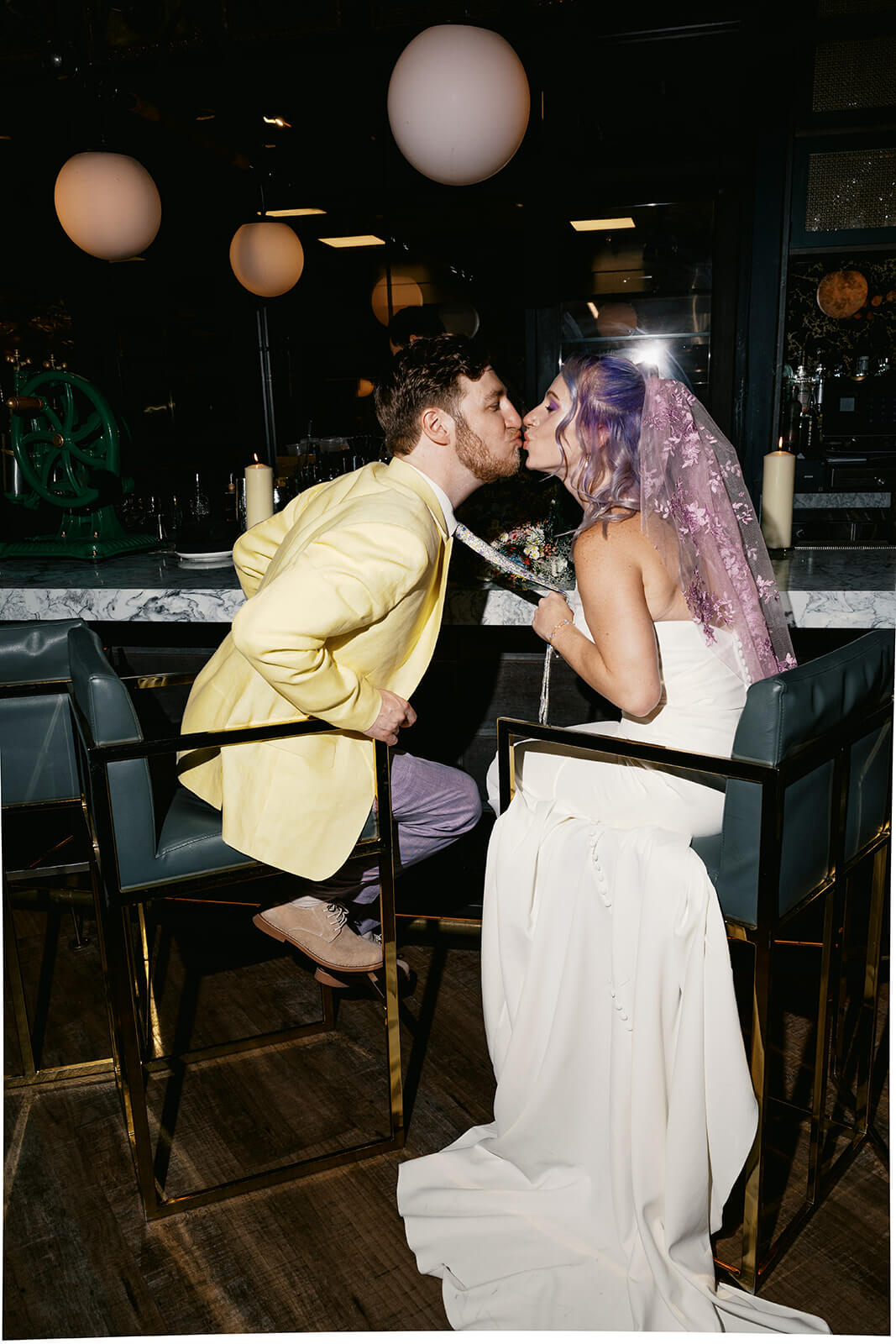 Newly married couple sharing a kiss during their intimate micro wedding reception at a stylish cocktail bar