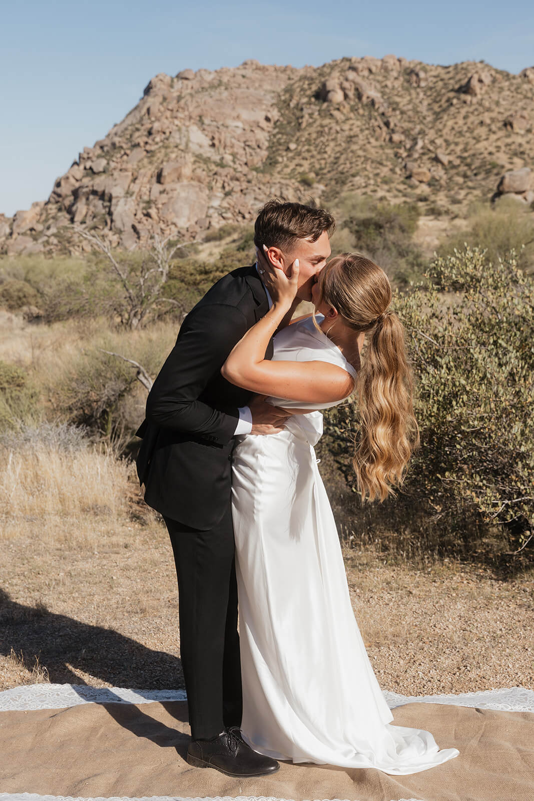 Bride and groom kissing in the Arizona desert during a modern intimate wedding ceremony