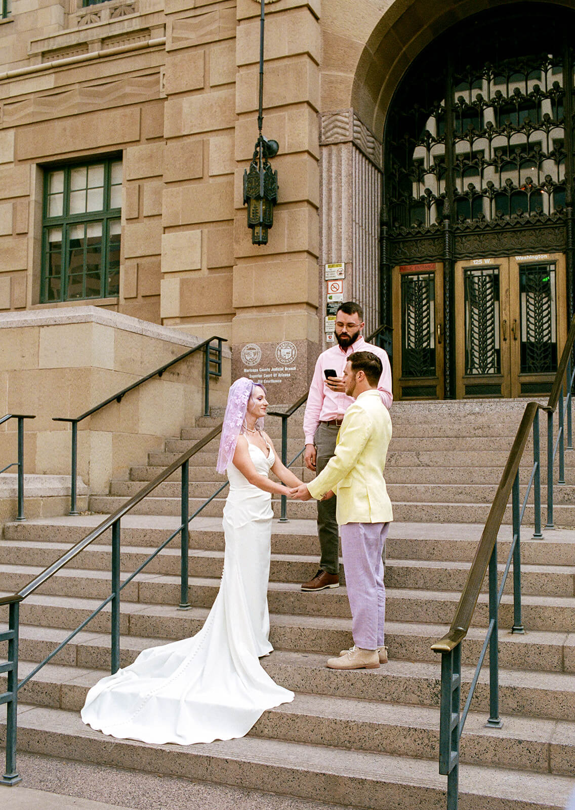 Couple exchanging vows on courthouse steps during a colorful modern elopement ceremony