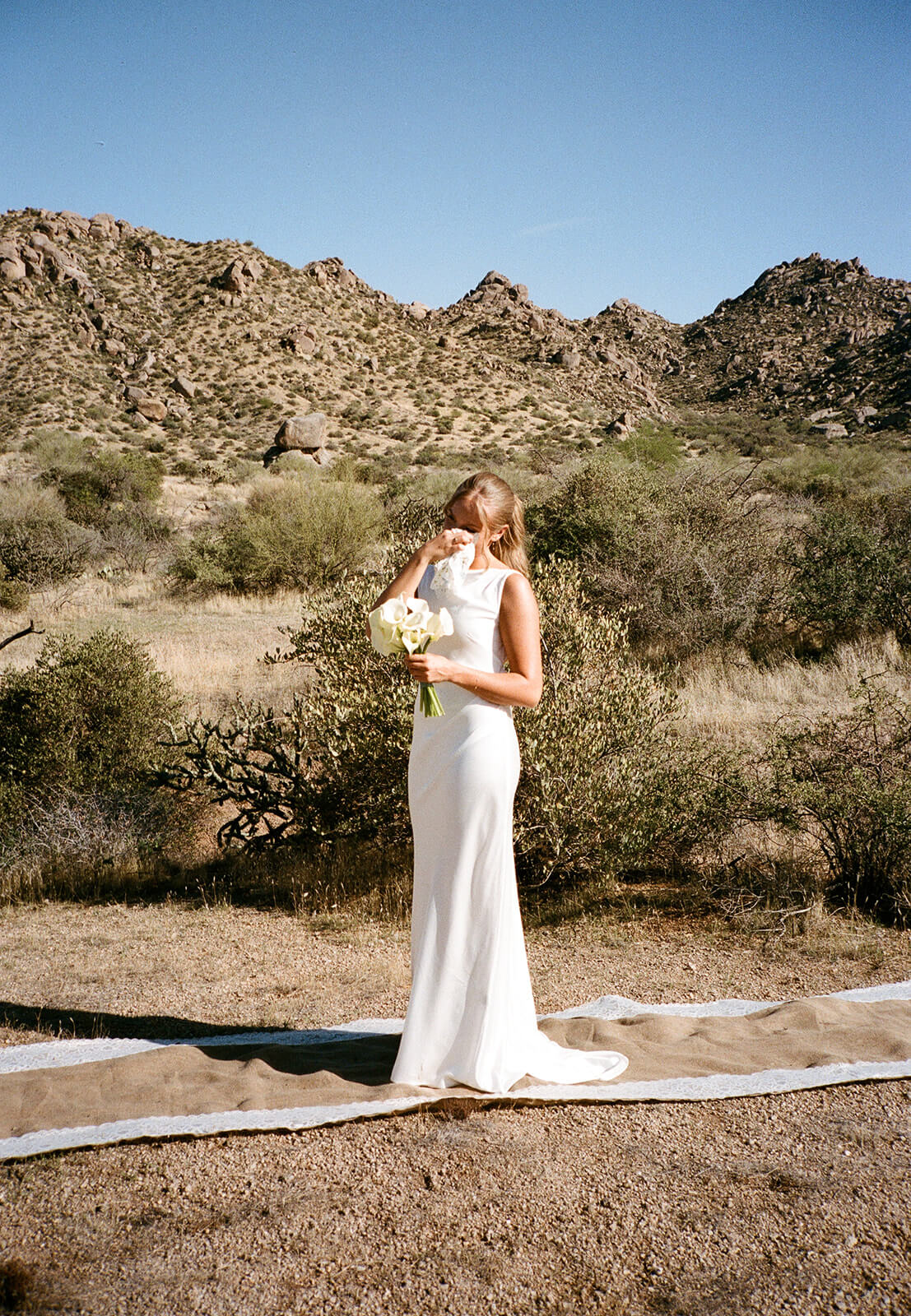 Minimalist bride standing alone in the desert before her intimate micro wedding ceremony