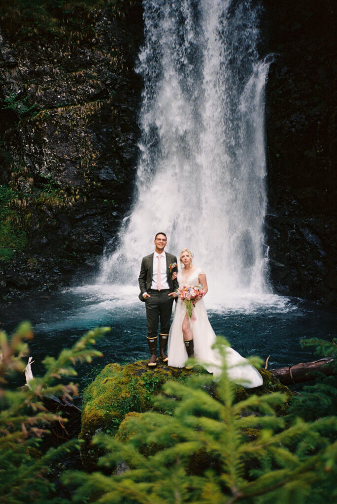 Bride and groom posing in front of a waterfall during a nature-inspired elopement ceremony