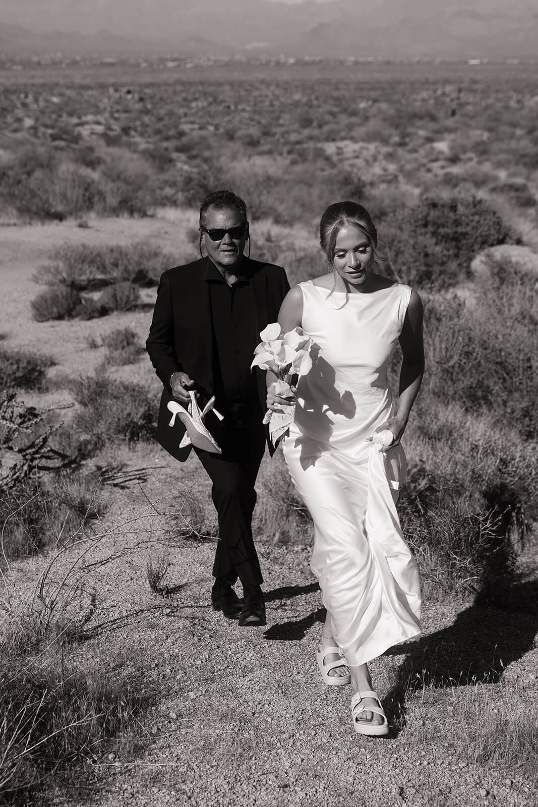Bride walking through the desert with officiant before a private outdoor elopement ceremony