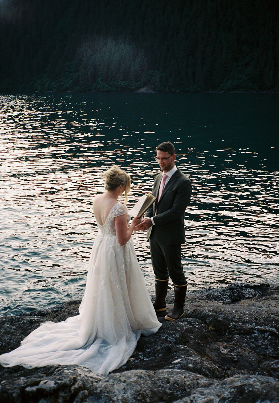 Couple exchanging vows beside a mountain lake during an adventurous waterfront elopement