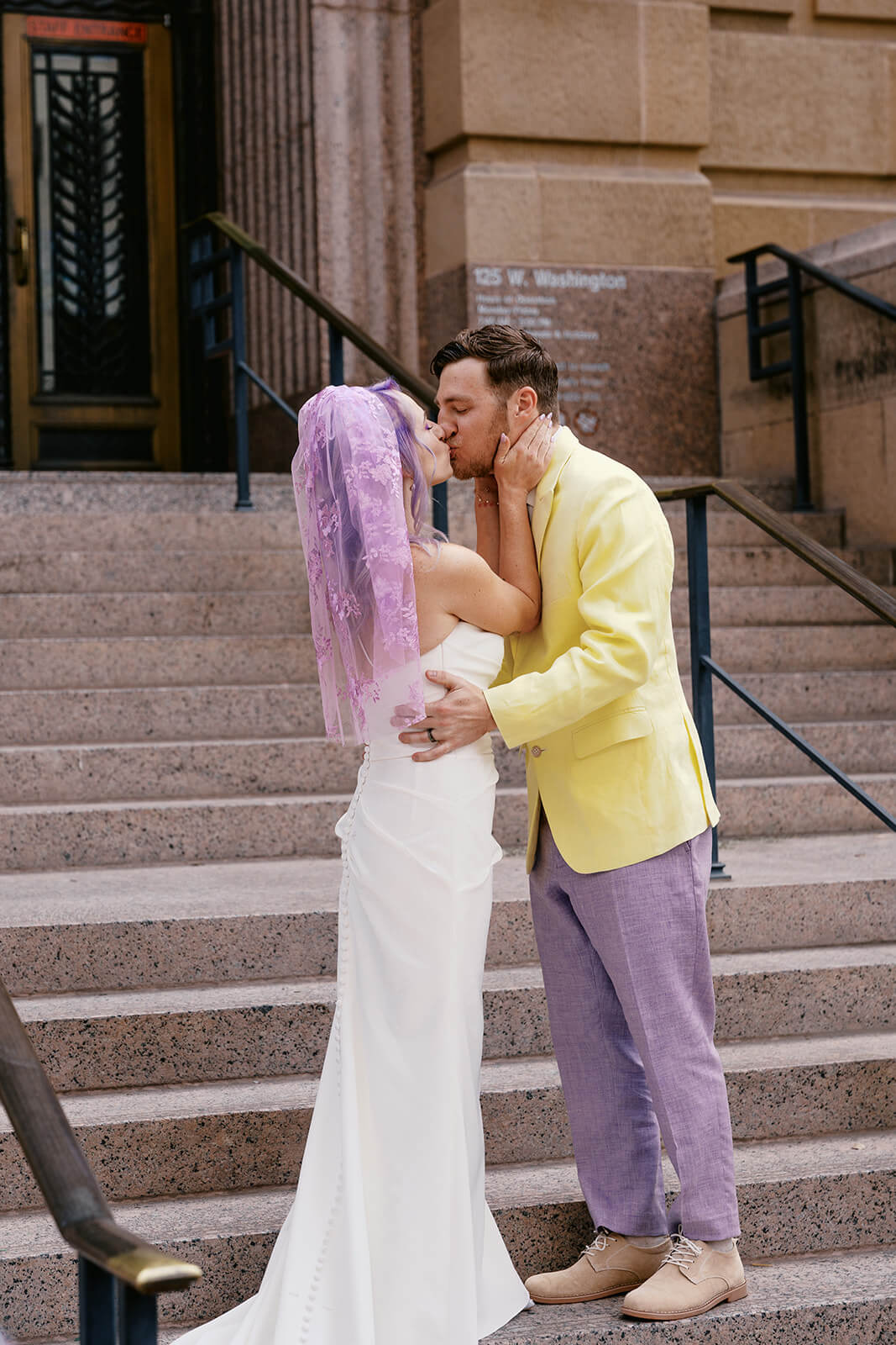 Newly married couple kissing on courthouse steps after their intimate city elopement