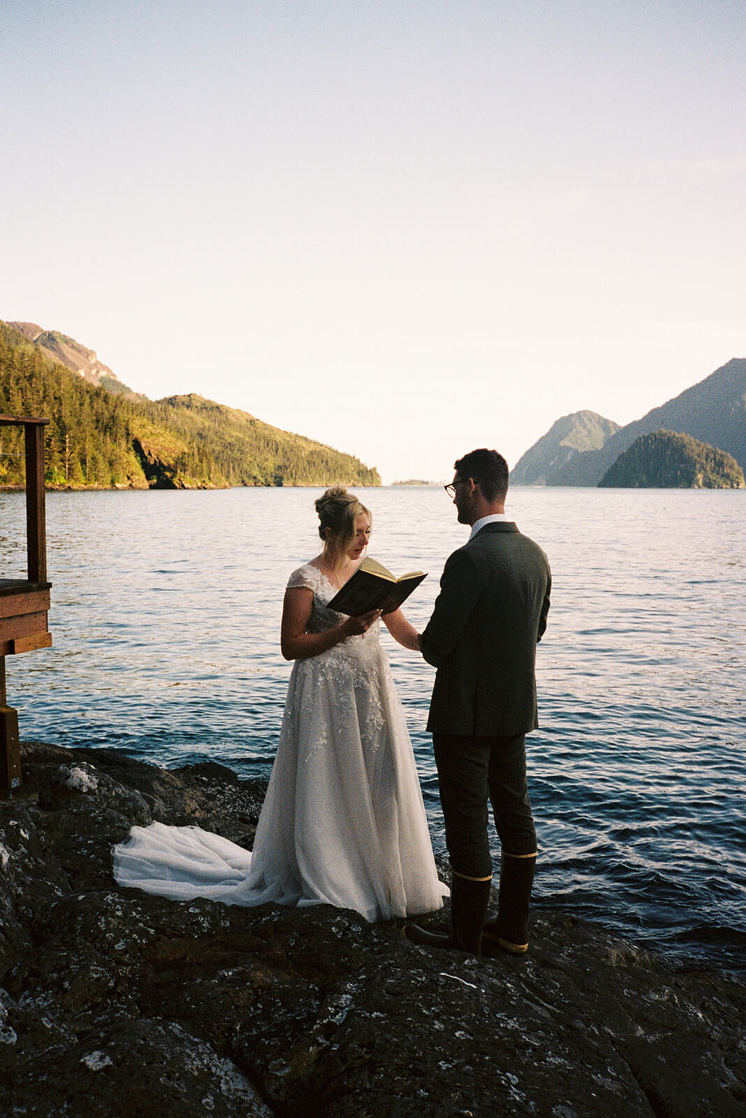 Bride reading private vows during a waterfront micro wedding ceremony surrounded by forested mountains