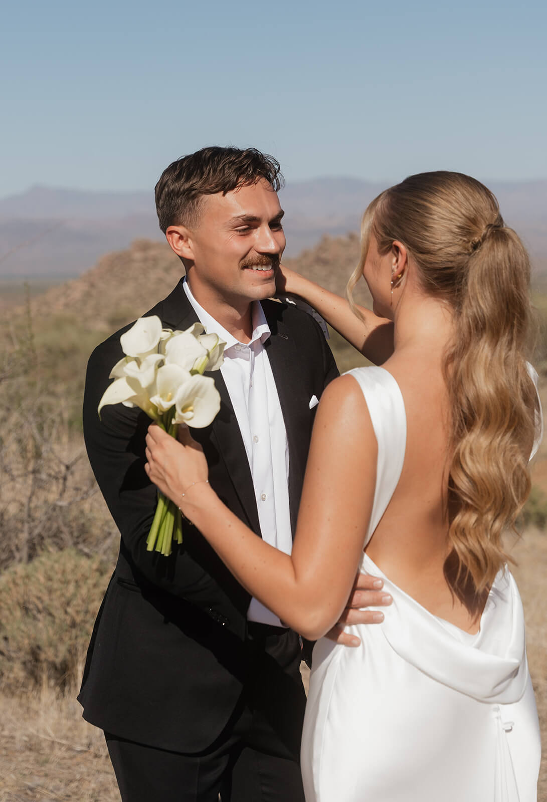 Bride and groom embracing in the Arizona desert during a modern micro wedding with mountain views