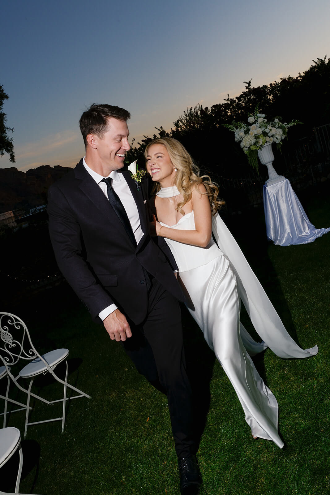 Newly married couple laughing together during an intimate outdoor wedding reception at sunset