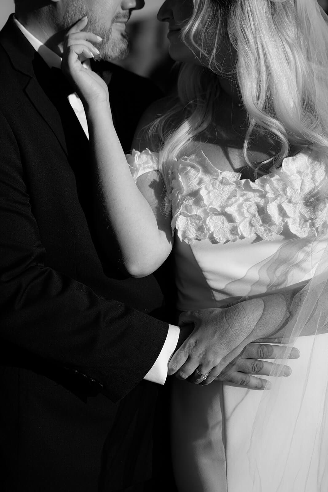 Black and white close-up photo of the bride and groom embracing during their wedding portrait session.