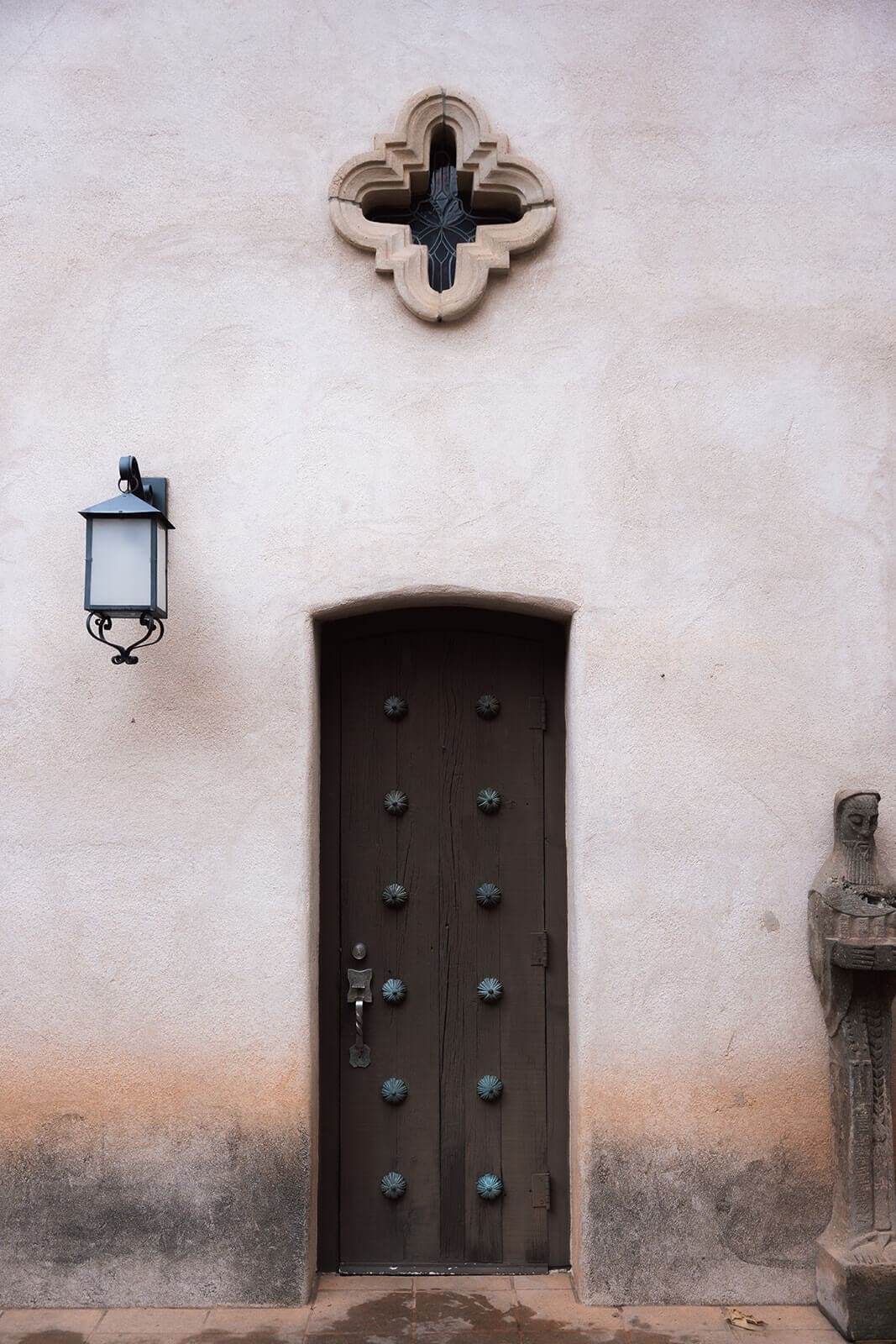 Large wooden door set into a stucco wall with Spanish-style architectural details at Tlaquepaque.